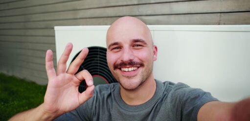 Uśmiechnięty mężczyzna na tle pompy ciepła GeniaAir Split marki Saunier Duval