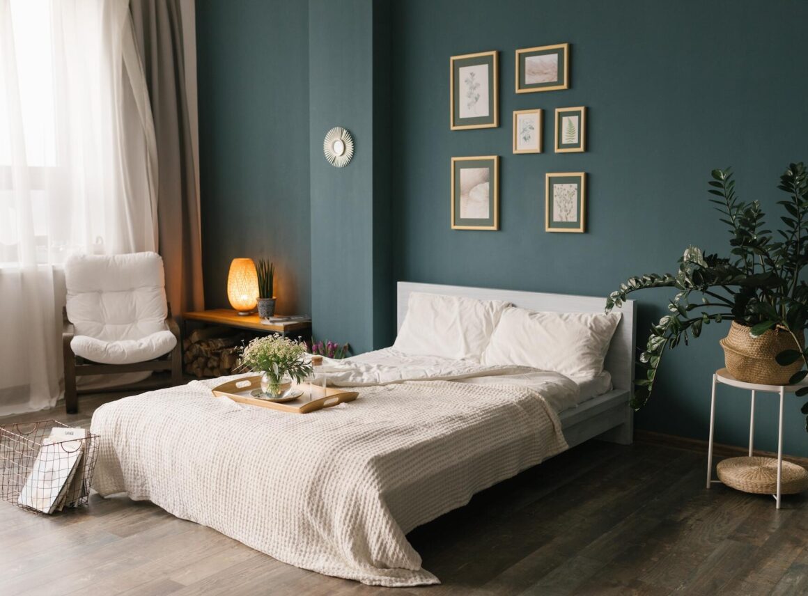 sypialnia z ciemnozielonymi ścianami i łóżkiem z białą narzutą